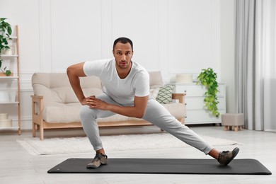 Man doing morning exercise on fitness mat at home