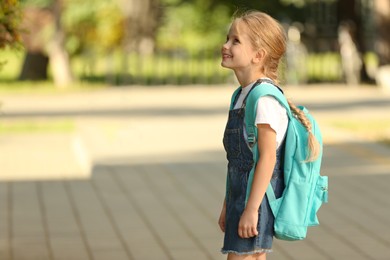 Photo of Little girl with backpack on way to school. Space for text