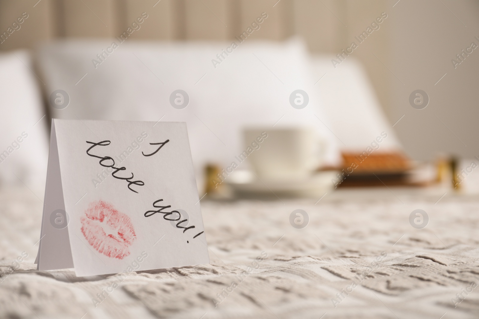 Photo of Romantic paper note I Love You on bed, closeup