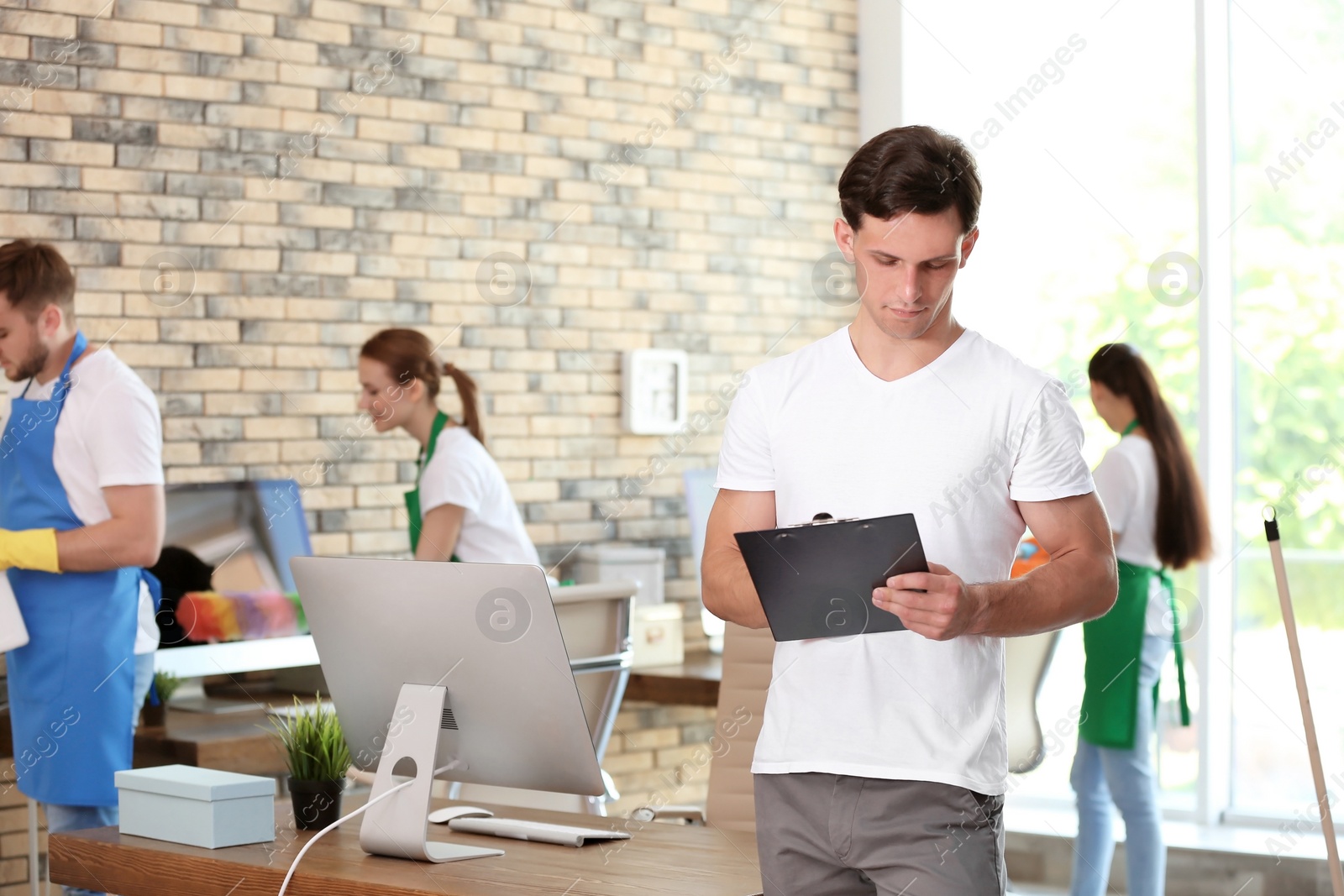 Photo of Team of professional janitors in uniform indoors