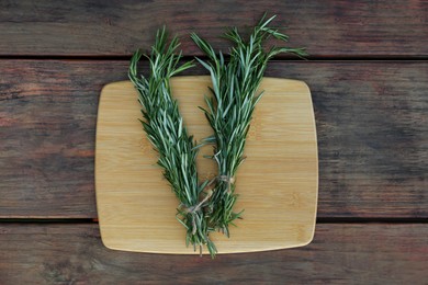 Photo of Bunches of fresh rosemary on wooden table, top view. Aromatic herb