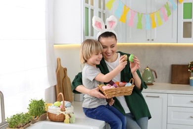 Mother and her son with Easter eggs in kitchen