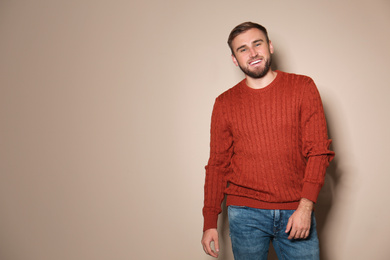 Handsome man wearing warm sweater on beige background. Space for text