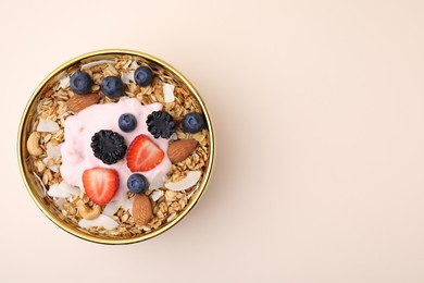 Photo of Tasty granola, yogurt and fresh berries in bowl on beige background, top view with space for text. Healthy breakfast