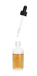 Photo of Essential oil dripping from pipette into glass bottle on white background