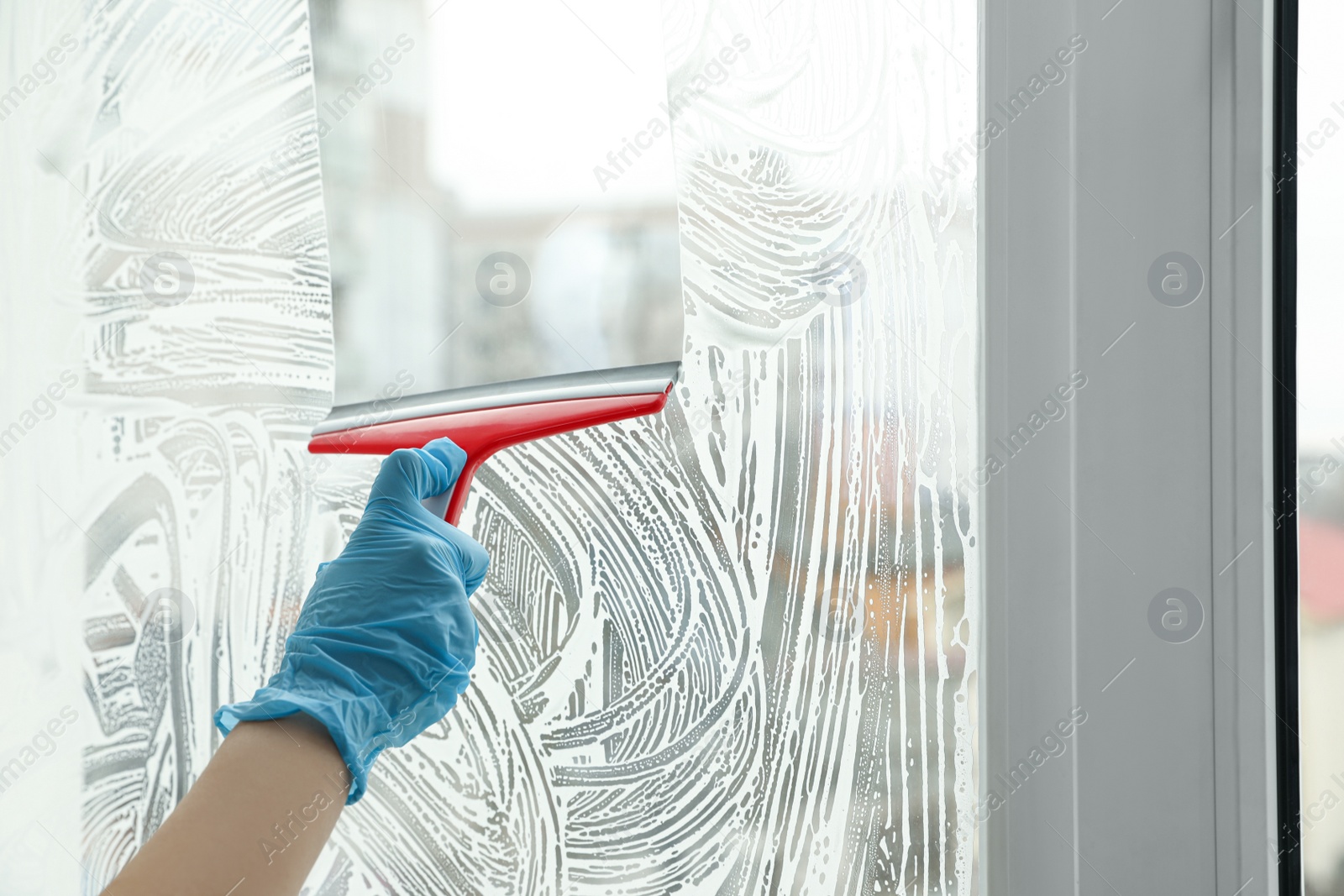 Photo of Woman cleaning window with squeegee indoors, closeup