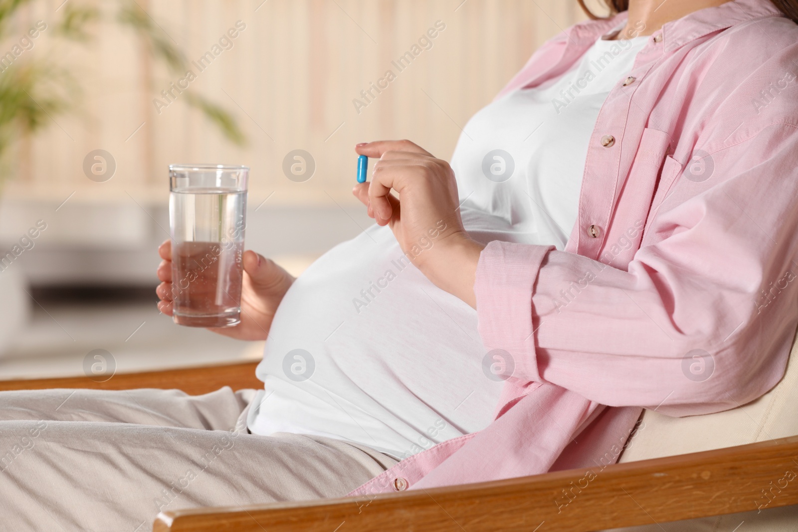 Photo of Pregnant woman taking pill at home, closeup