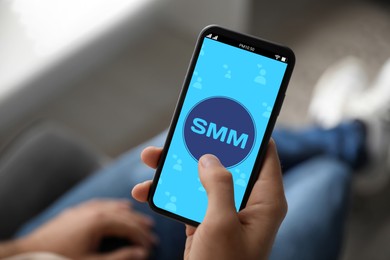 Image of SMM (Social Media Marketing) concept. Man using smartphone indoors, closeup