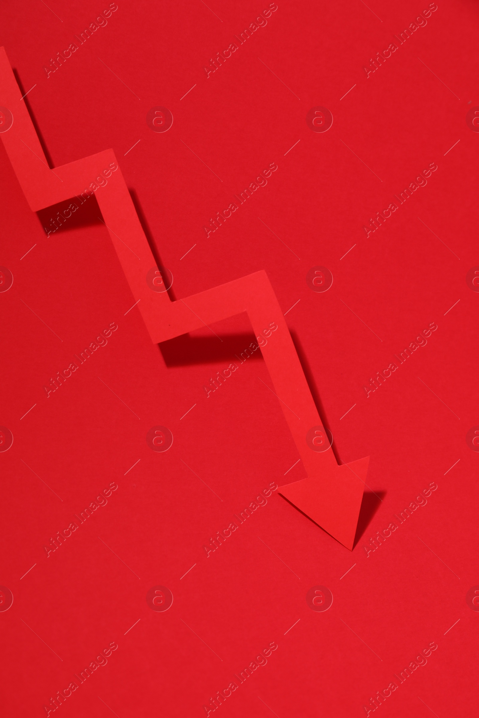 Photo of One zigzag paper arrow on red background, top view