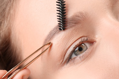 Photo of Young woman having eyebrow correction procedure in beauty salon, closeup