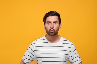 Handsome man blowing kiss on orange background