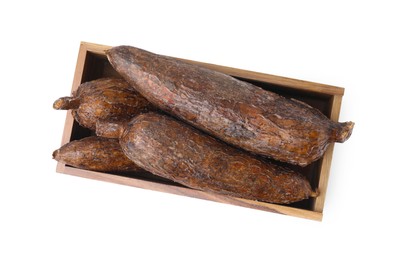 Photo of Whole cassava roots in wooden crate isolated on white, top view