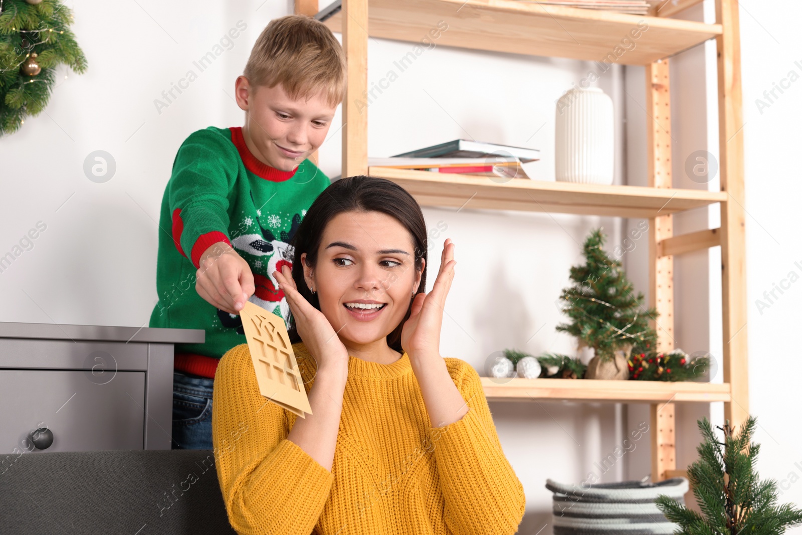 Photo of Happy woman receiving greeting card from her son at home