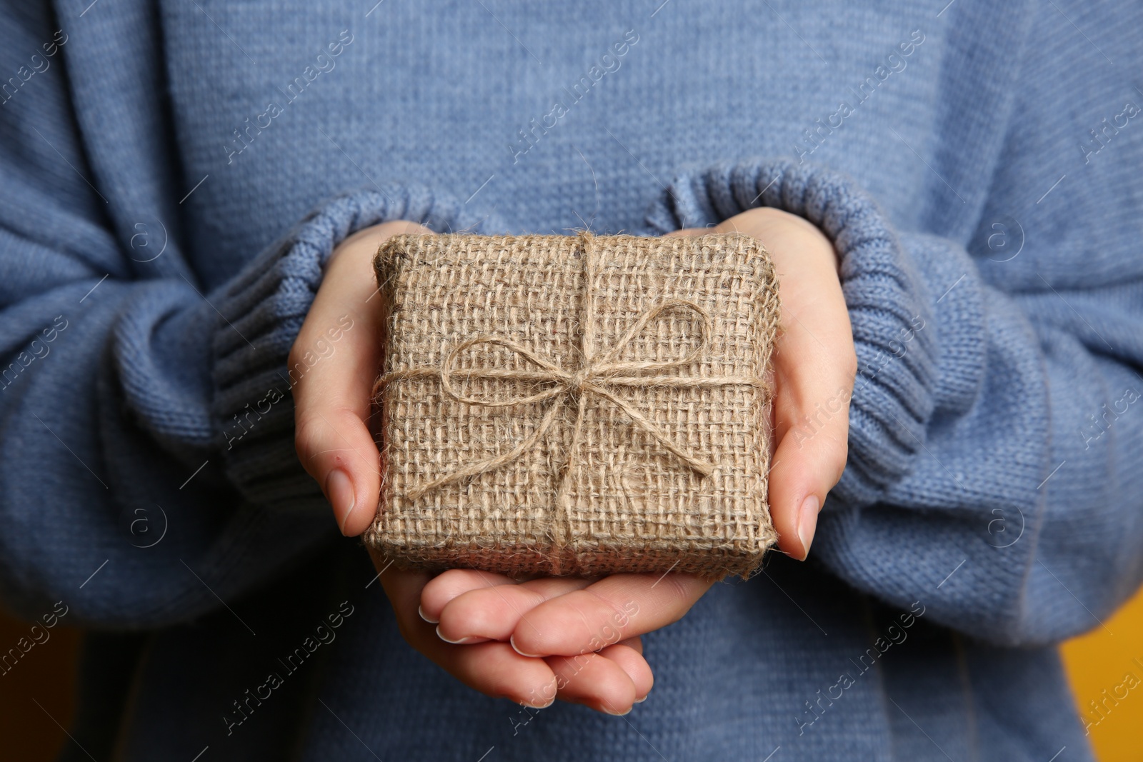 Photo of Woman in blue sweater holding Christmas gift box, closeup