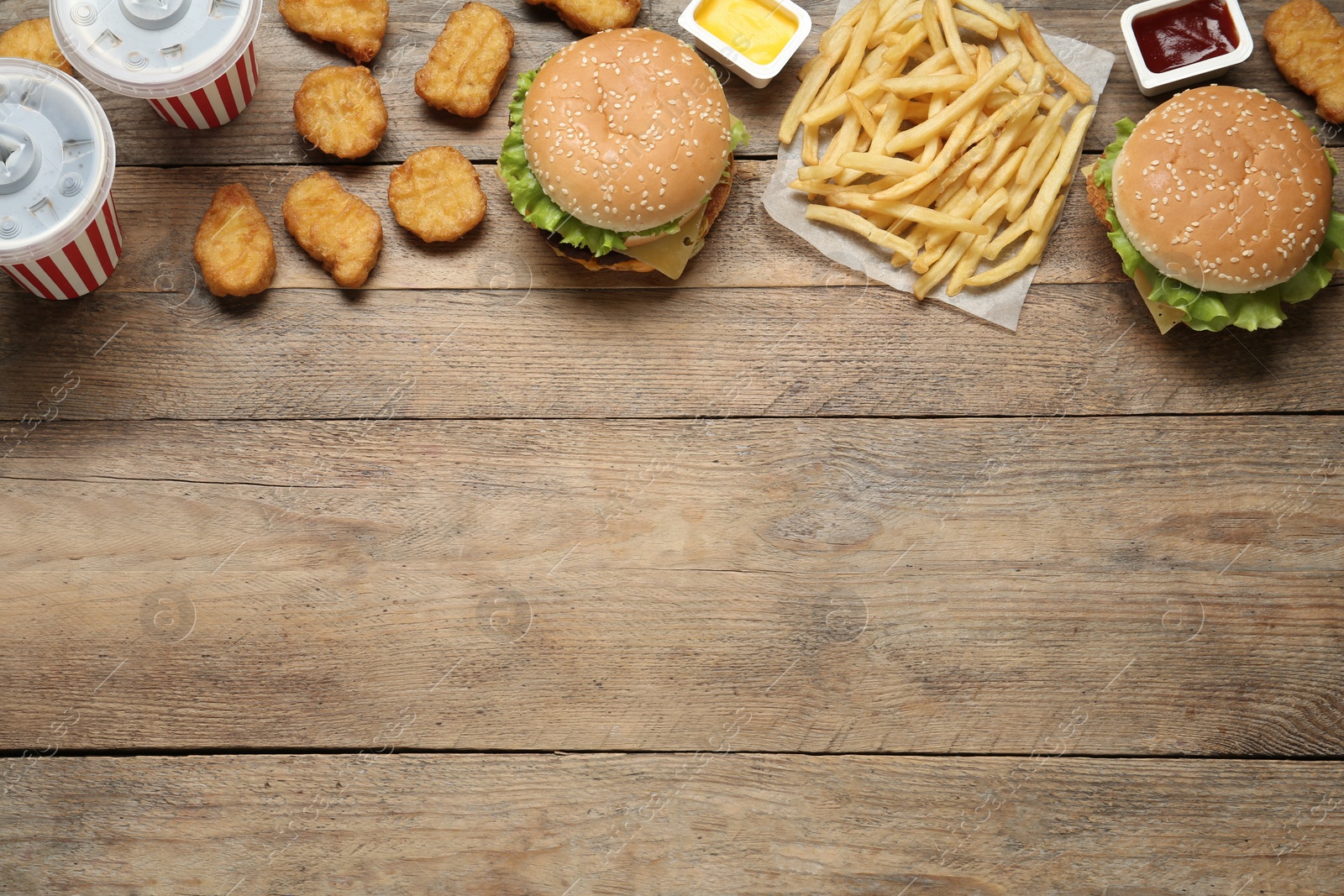 Photo of Flat lay composition with delicious fast food menu on wooden table. Space for text