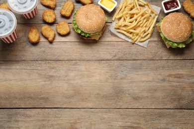 Flat lay composition with delicious fast food menu on wooden table. Space for text