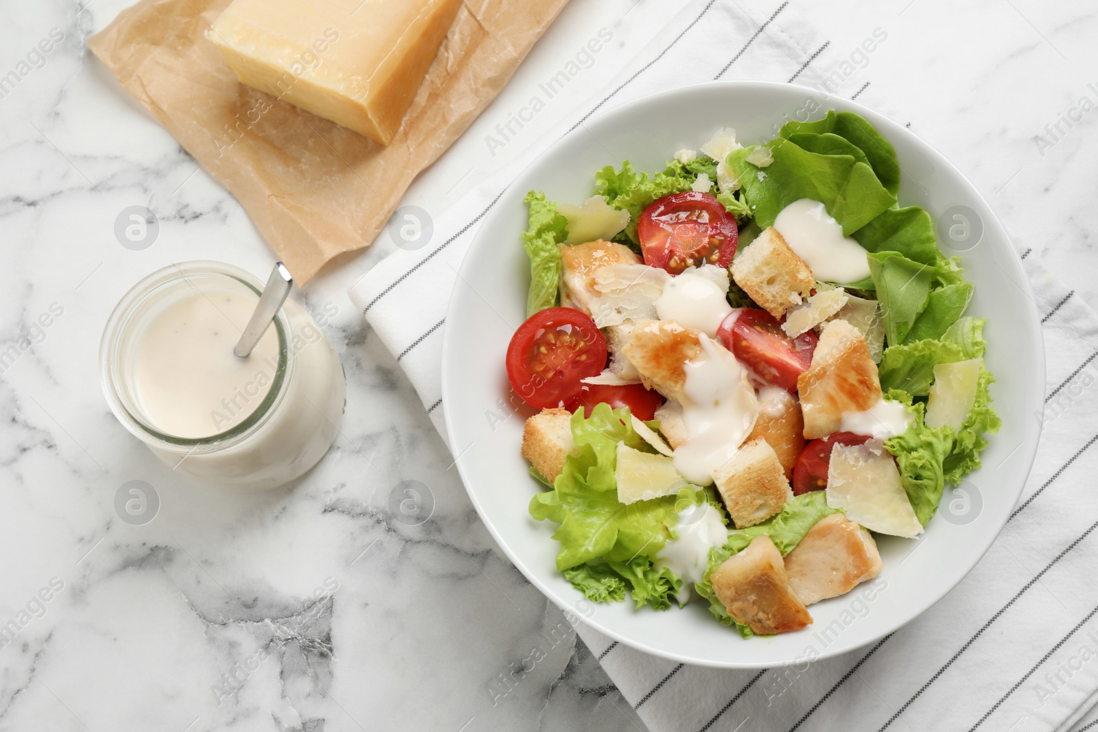 Photo of Tasty Caesar salad served on white marble table, flat lay