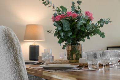 Beautiful table setting with bouquet indoors. Roses and eucalyptus branches in vase