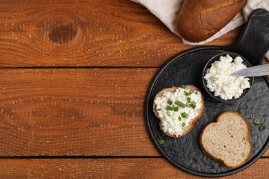 Bread with cottage cheese and green onion on wooden table, flat lay. Space for text