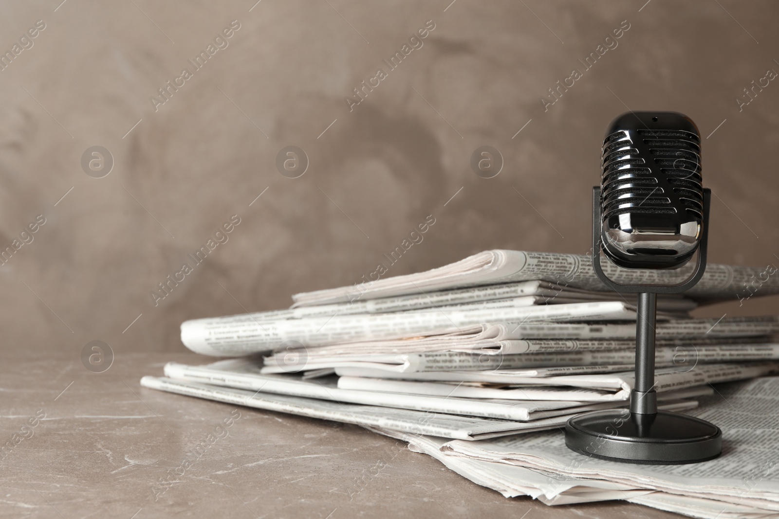 Photo of Newspapers and vintage microphone on marble table. Journalist's work