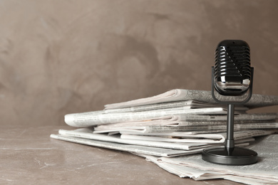 Photo of Newspapers and vintage microphone on marble table. Journalist's work