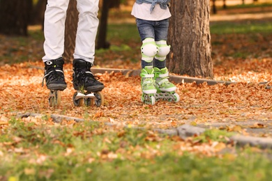 Photo of Father and his daughter roller skating in autumn park