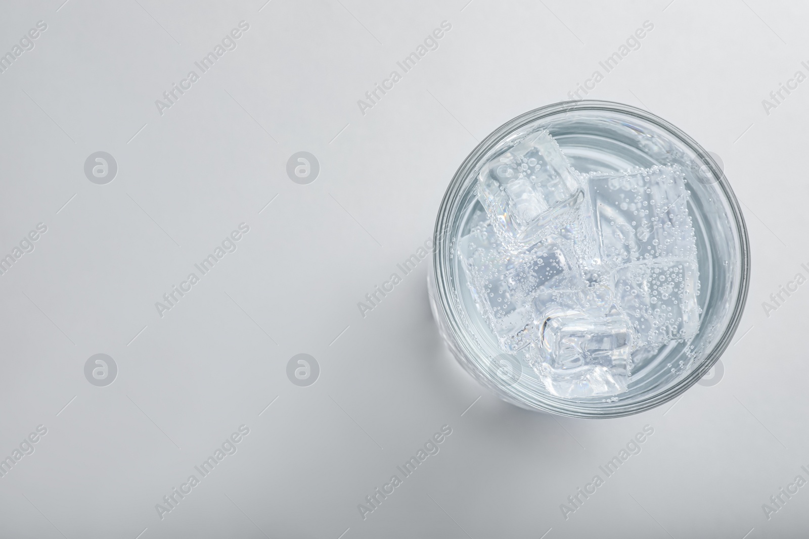 Photo of Glass of soda water with ice isolated on white, top view