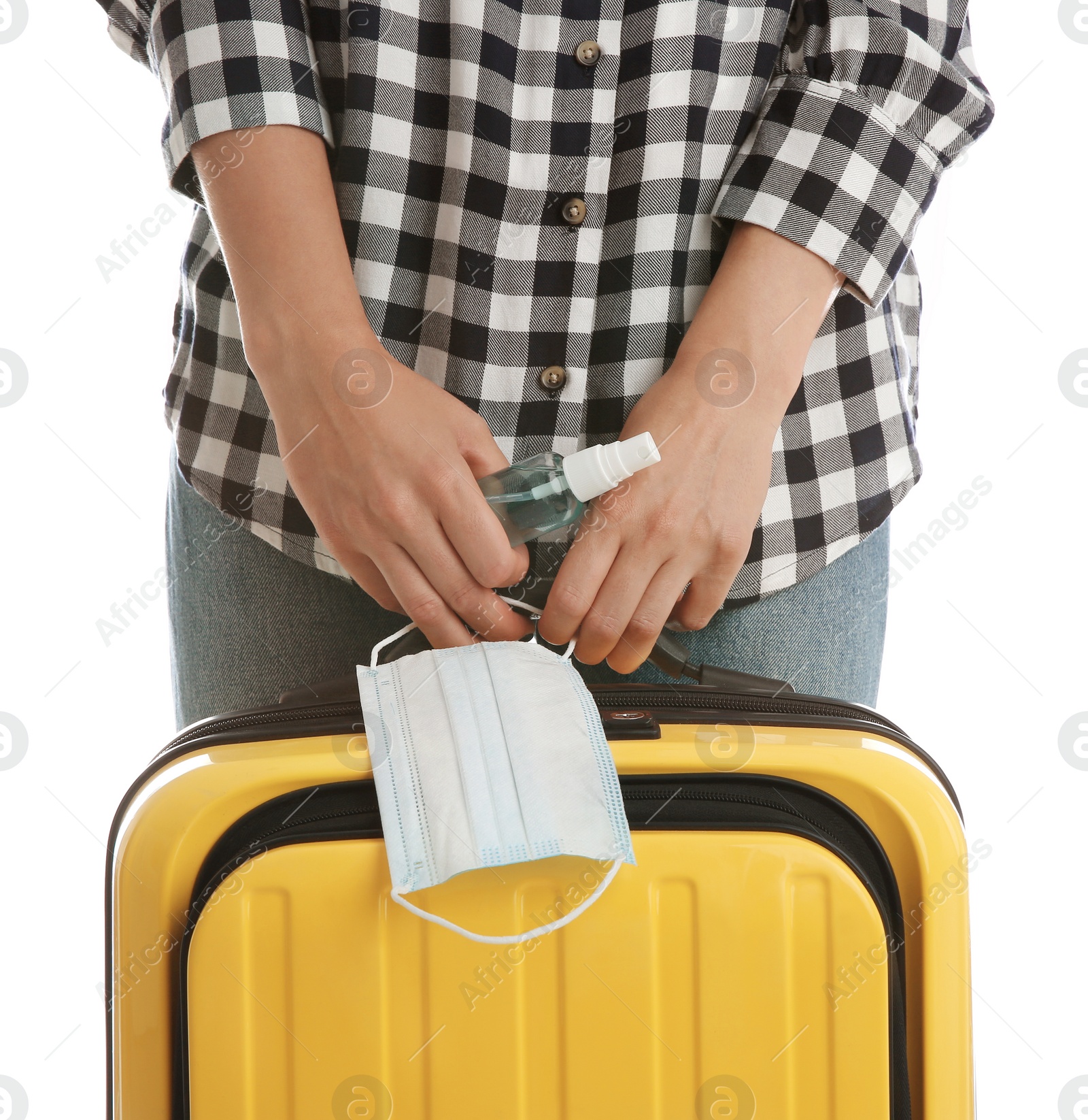 Photo of Woman with suitcase, antiseptic spray and protective mask on white background, closeup. Travelling during coronavirus pandemic