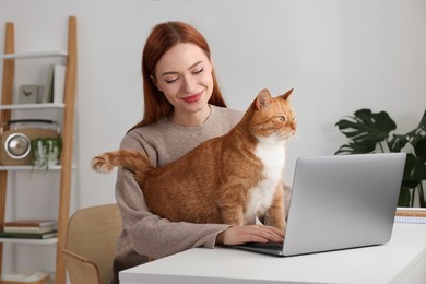 Photo of Woman with cat working at desk. Home office