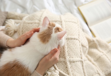 Photo of Woman with cute fluffy cat and book on bed, above view