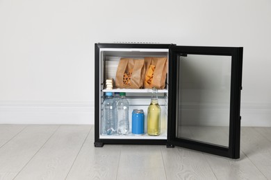 Photo of Mini bar filled with food and drinks near white wall indoors