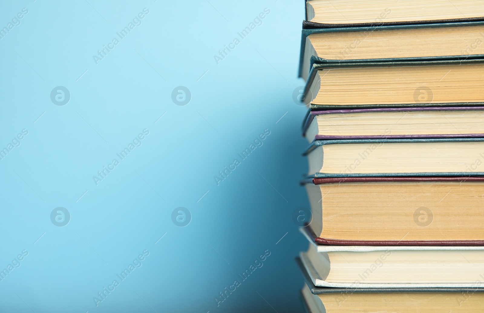 Photo of Stack of hardcover books on light blue background, space for text