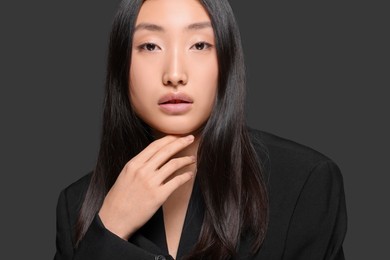 Portrait of beautiful young Asian woman on black background