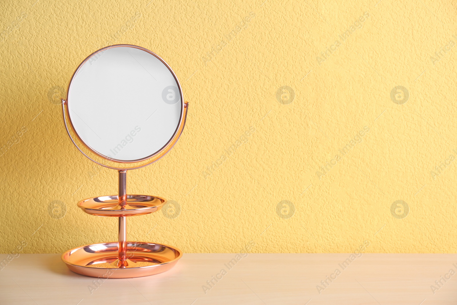 Photo of Mirror with accessory holder on table near color wall