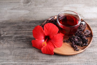 Photo of Delicious hibiscus tea and flowers on wooden table. Space for text