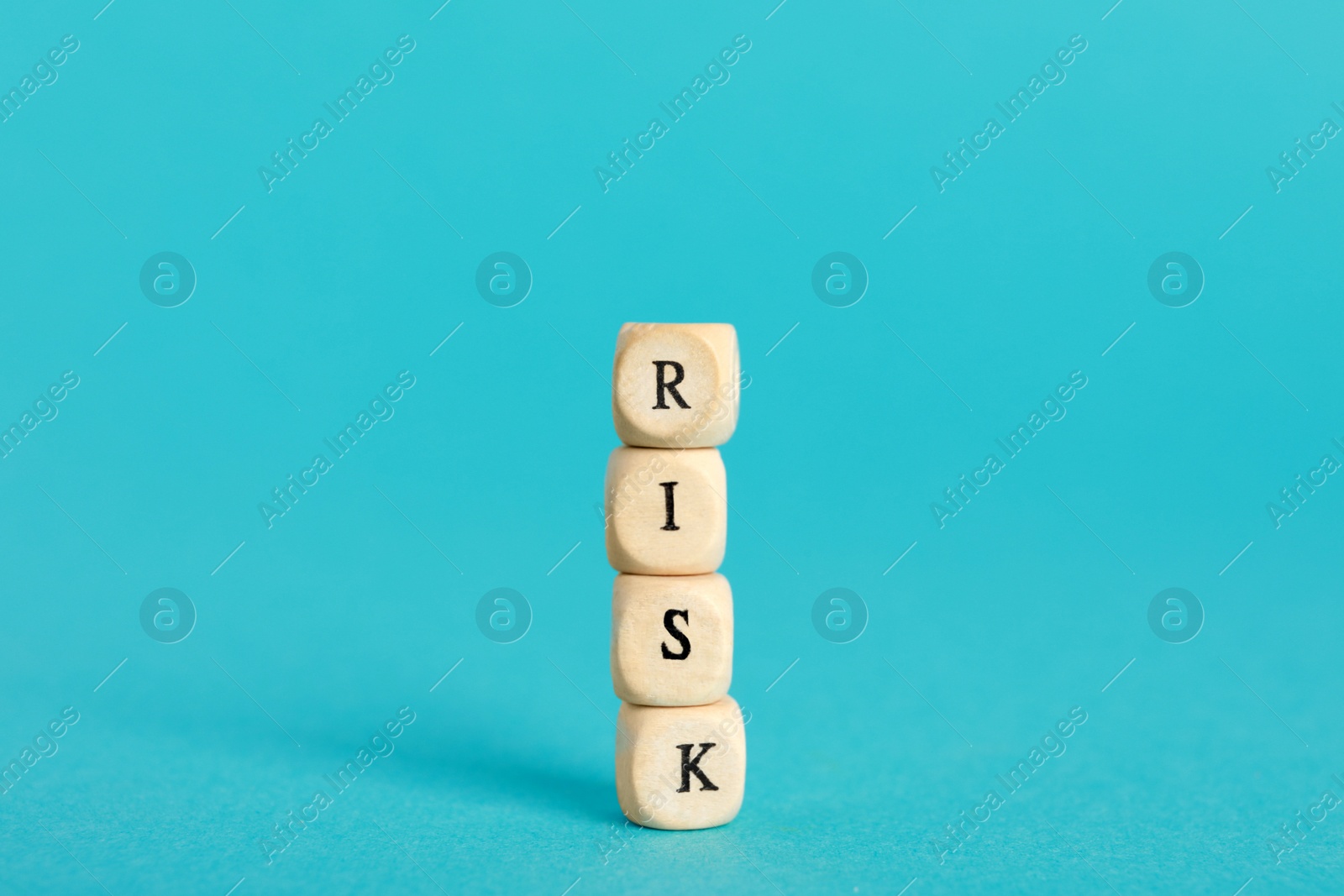 Photo of Word Risk made of small wooden cubes on turquoise background