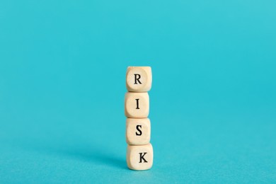 Photo of Word Risk made of small wooden cubes on turquoise background