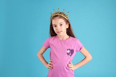 Photo of Cute girl in golden crown with gems on light blue background. Little princess