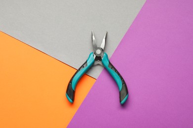 Photo of Bent nose pliers on color background, top view