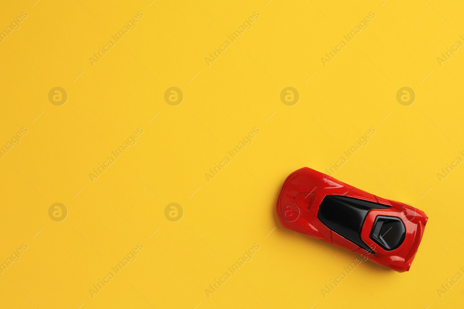 Photo of One red car on yellow background, top view with space for text. Children`s toy