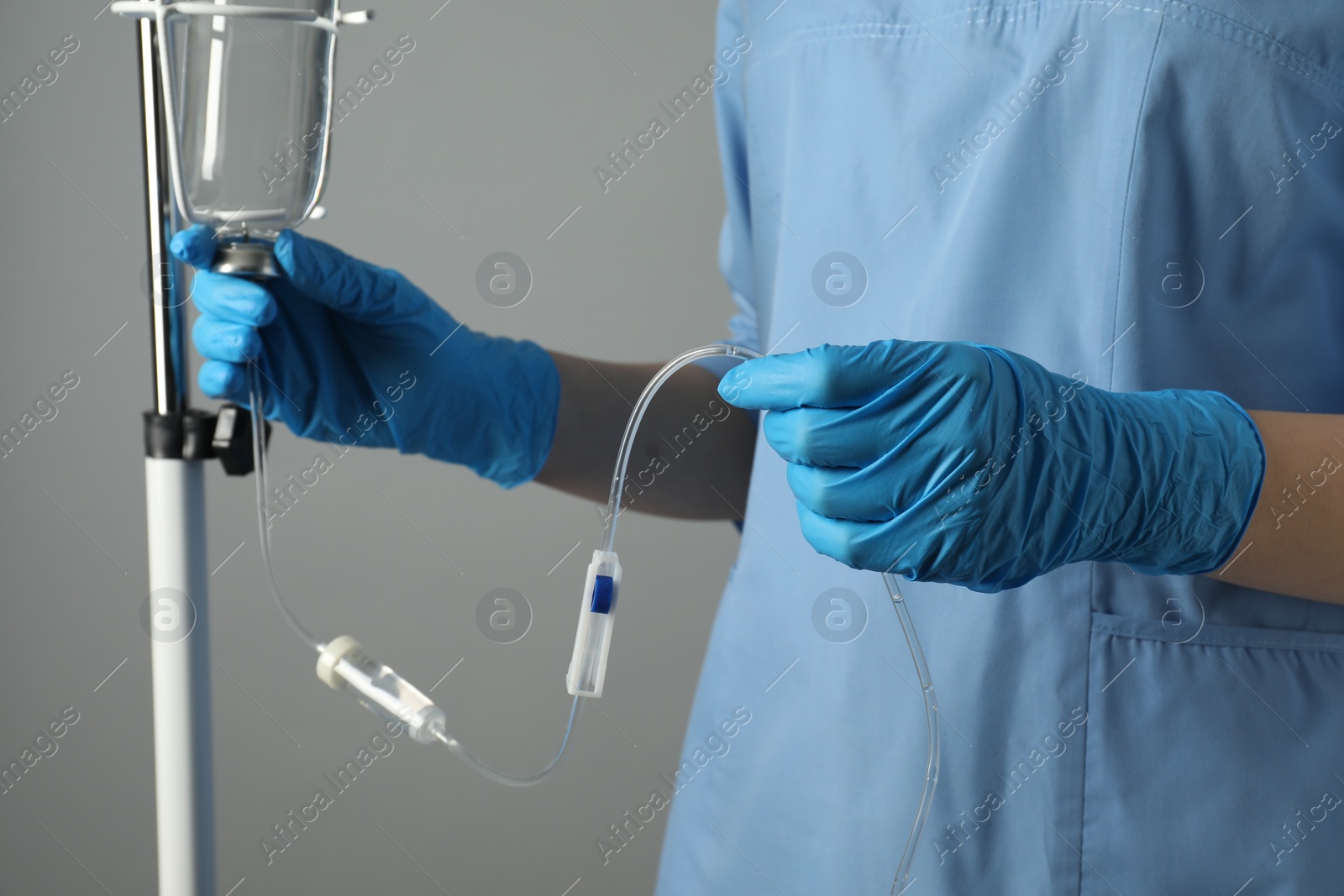 Photo of Nurse with IV infusion set on grey background, closeup