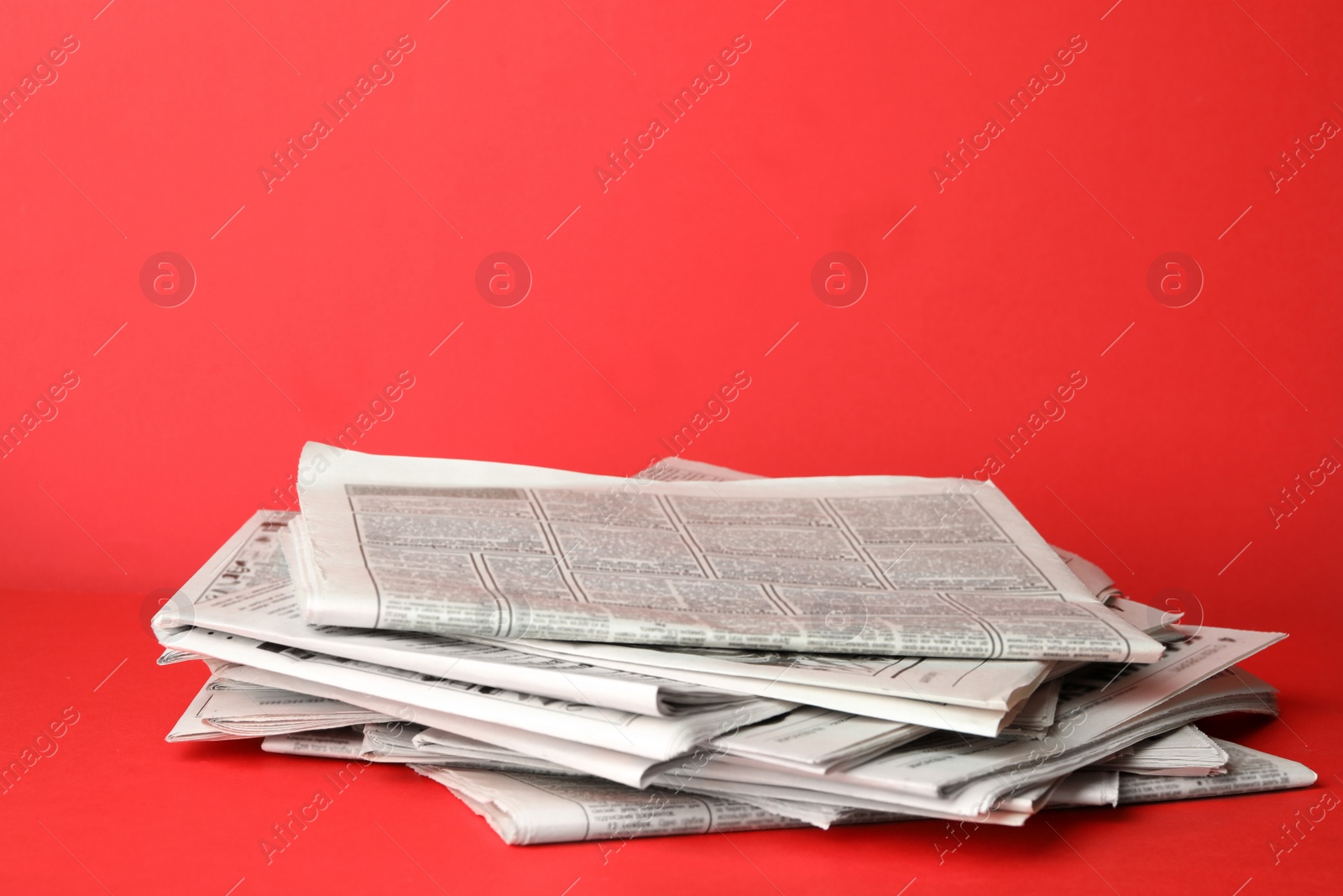 Photo of Stack of newspapers on red background. Journalist's work