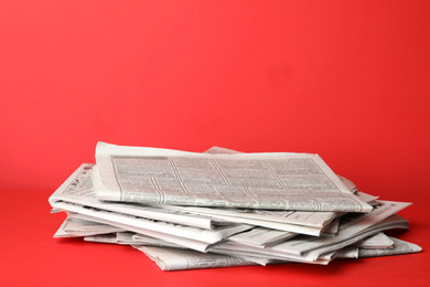 Stack of newspapers on red background. Journalist's work