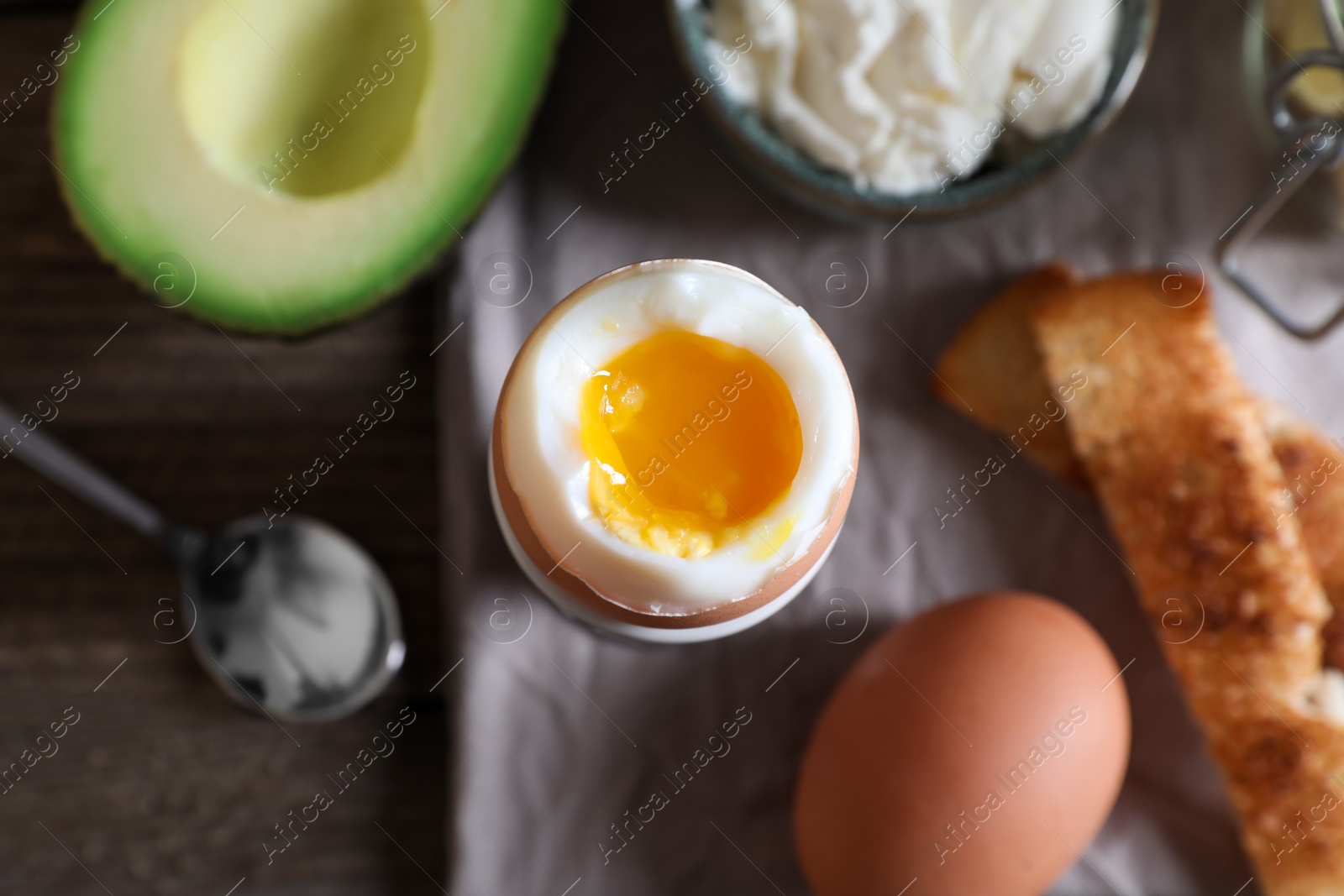 Photo of Soft boiled egg served for breakfast on wooden table, flat lay