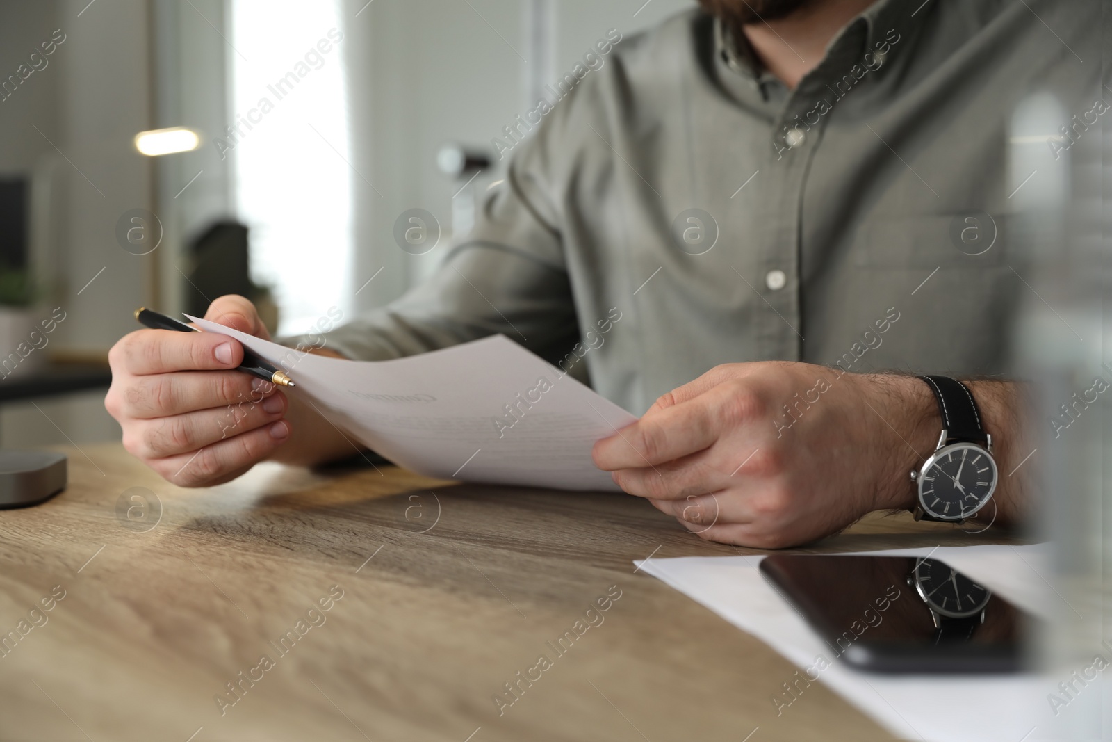 Photo of Businessman working with documents at wooden desk in office, closeup