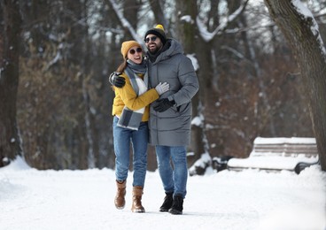 Photo of Happy young couple walking in snowy park on winter day