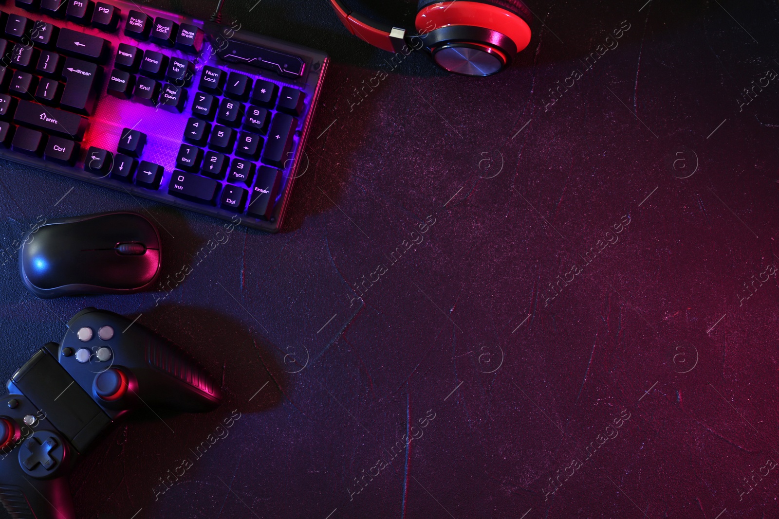 Photo of Modern RGB keyboard, mouse and video game controller on grey table, flat lay. Space for text