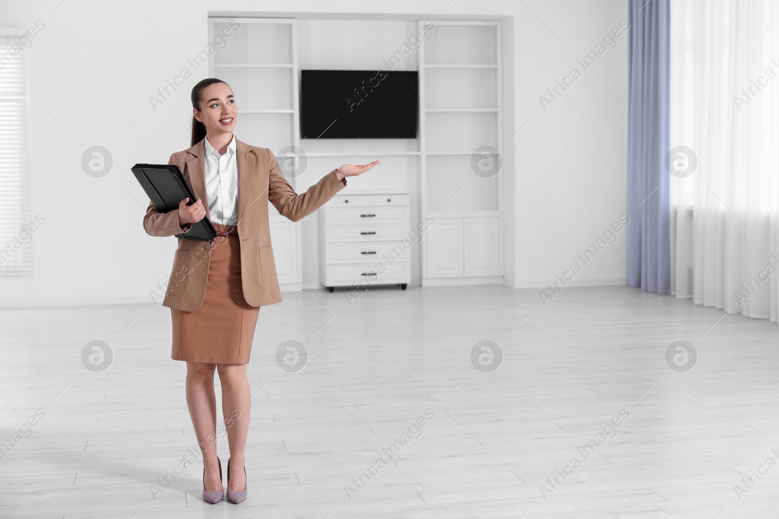 Photo of Happy real estate agent with leather portfolio showing new apartment