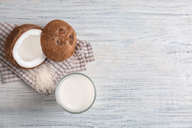 Glass with coconut milk on wooden background, top view