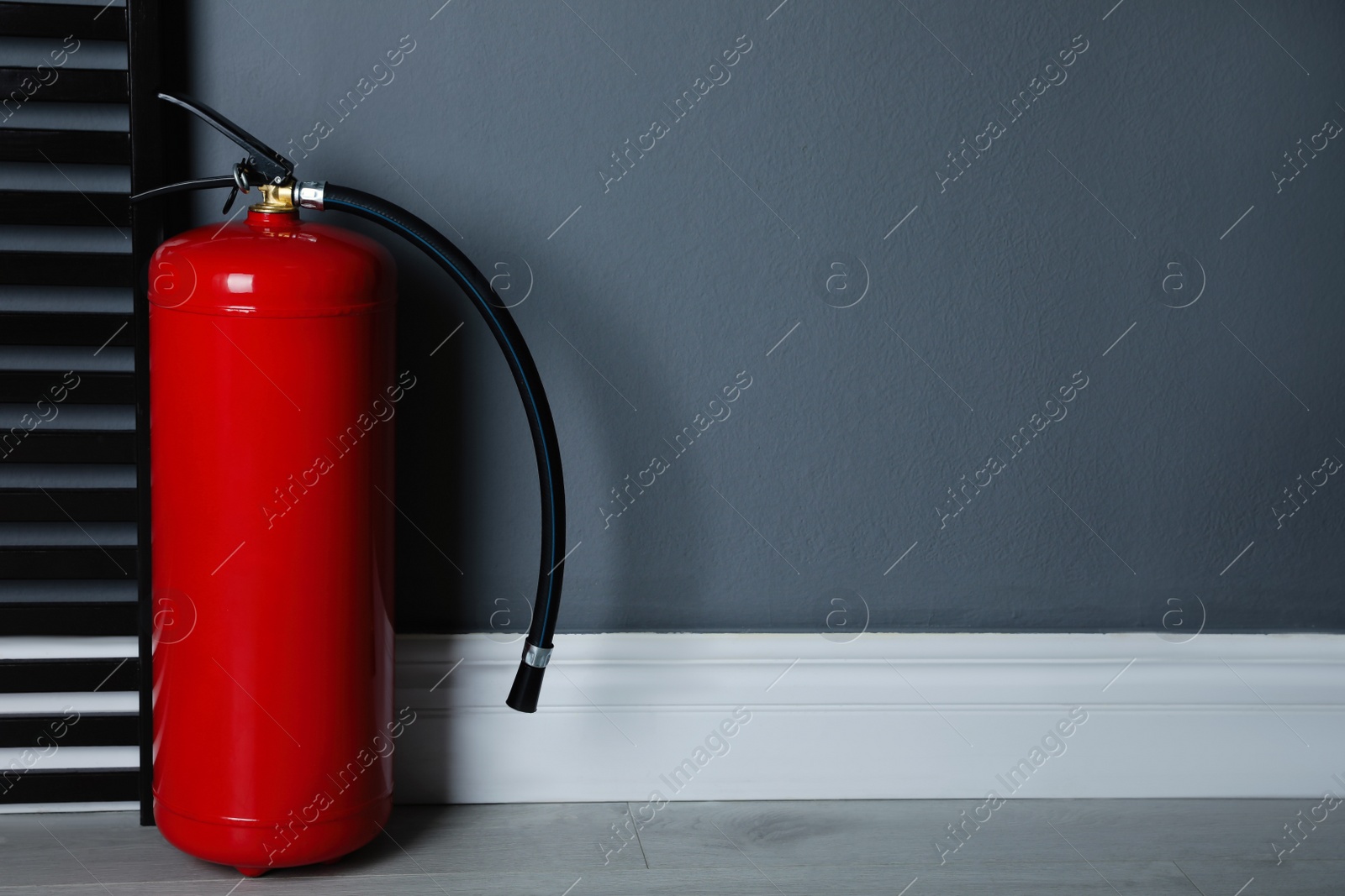 Photo of Fire extinguisher near grey wall indoors. Space for text